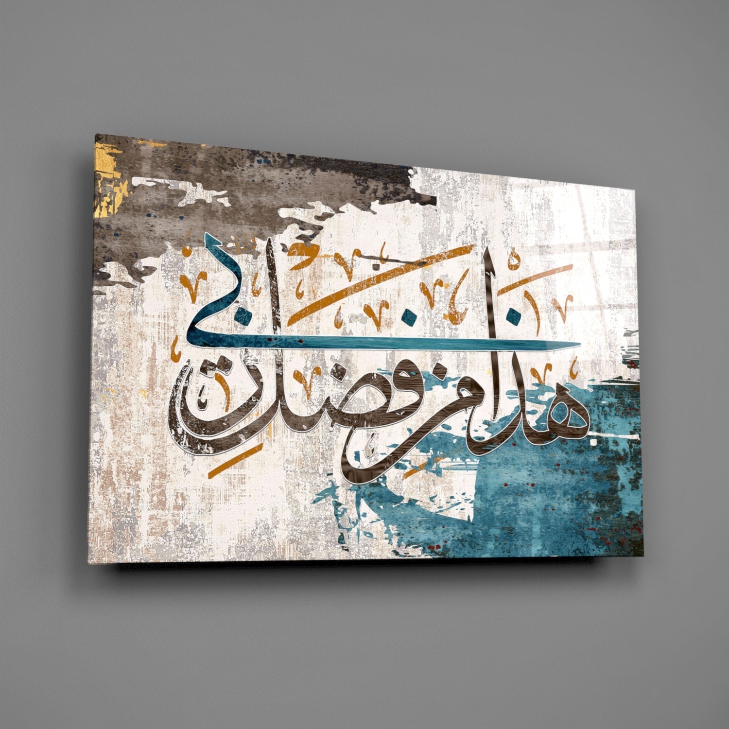 Glass wall art featuring Arabic calligraphy in brown and teal on distressed white and blue textured background, displayed at an angle.