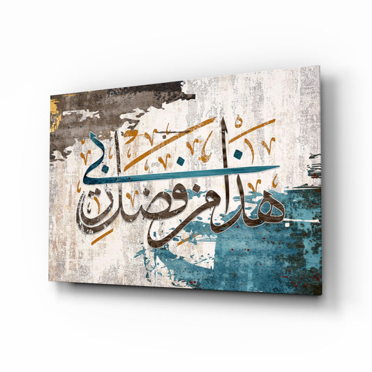 Angled perspective of glass wall art displaying Arabic calligraphy in brown and teal on distressed white and turquoise textured background.