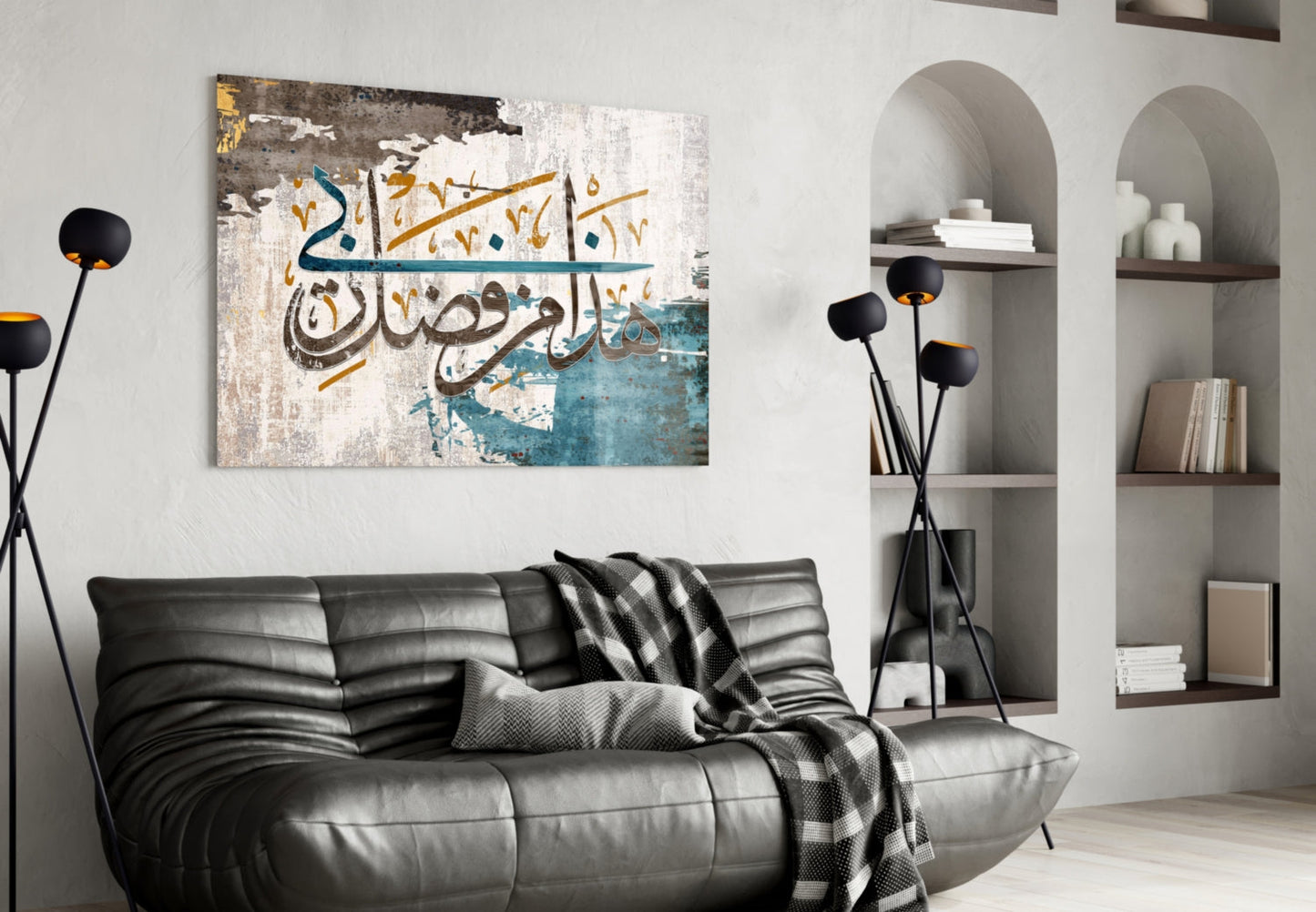 Modern living room interior with black leather sofa displaying Surah An-Naml glass wall art featuring Arabic calligraphy in blue, gold, and white tones above.
