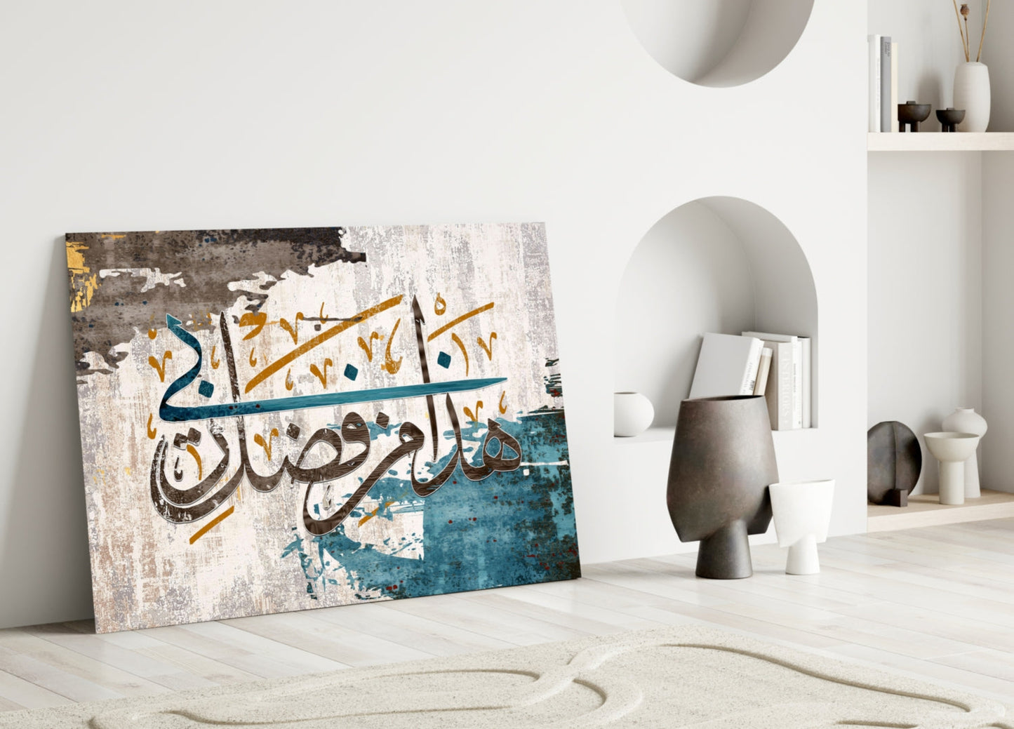 Surah An-Naml glass wall art leaning against white wall in minimalist interior with Arabic calligraphy in brown and gold on distressed blue and cream background.