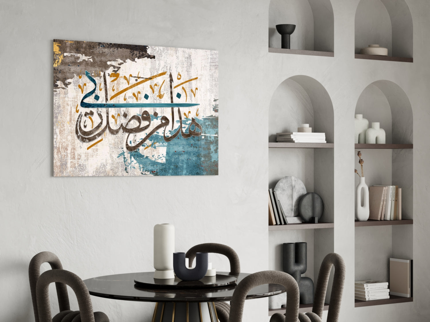 Surah An-Naml glass wall art with Arabic calligraphy in teal, gold, and cream displayed above a black round dining table with chairs.