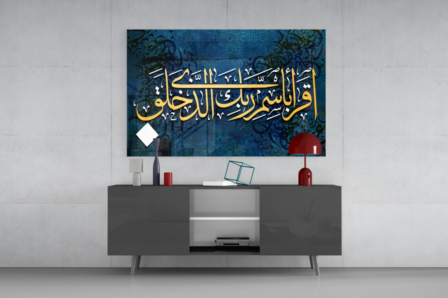 Blue glass wall art with gold Arabic calligraphy displayed above gray media console in modern interior setting.