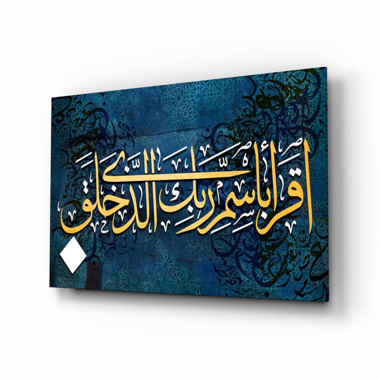 Angled perspective view of blue glass wall art with gold Arabic calligraphy and ornate black floral patterns on deep teal background.
