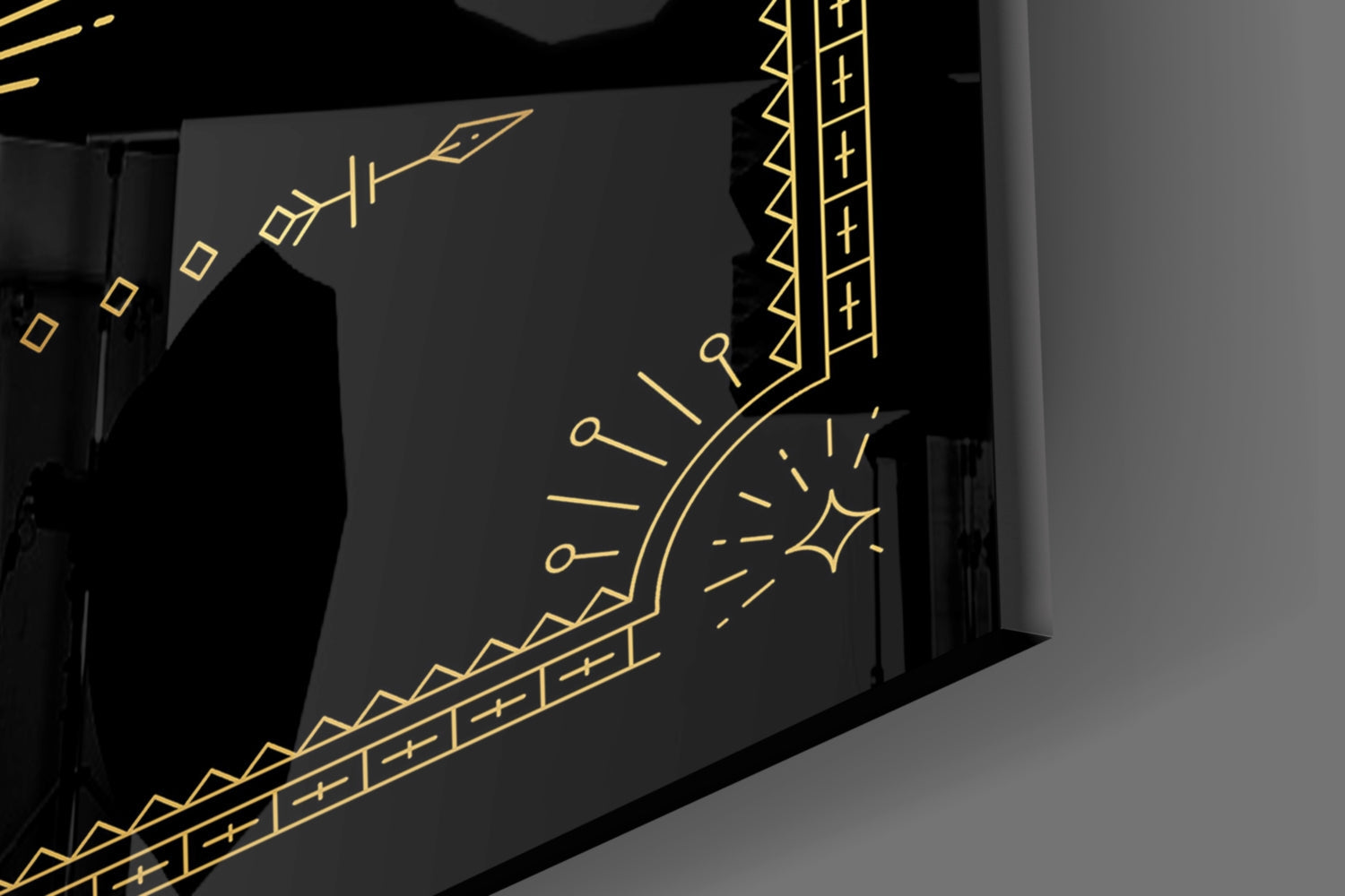 Gold line art design on black glass panel displayed at an angled perspective in interior setting.
