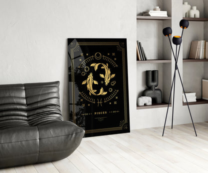 Black and gold Pisces zodiac glass wall art displayed in a modern living room with gray leather chair and white shelving.