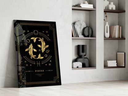Black glass Pisces zodiac art leaning against white wall beside wooden shelving with decorative objects and books.
